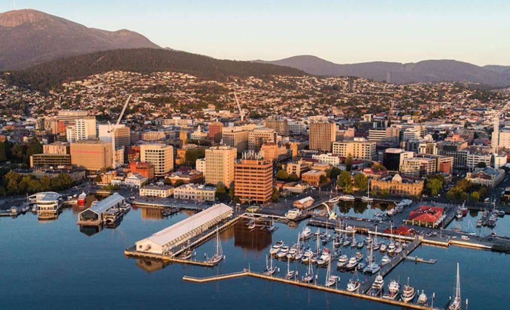 정박지에 정박한 보트, 다양한 건물, 언덕을 배경으로 펼쳐지는 해안 도시의 공중 전망.