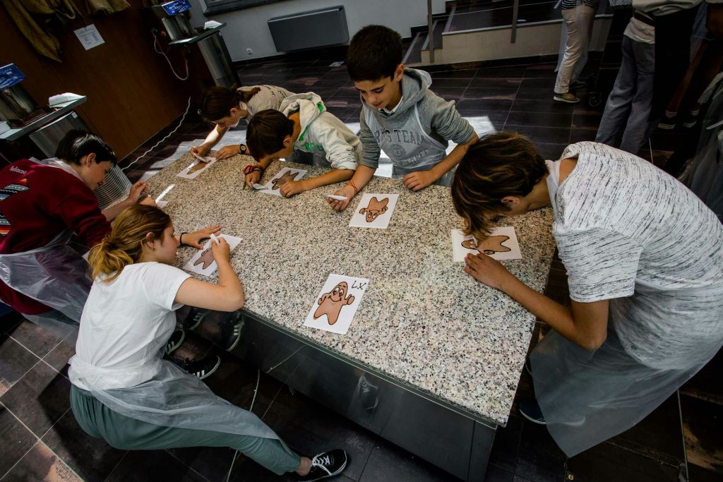 주방 카운터에서 아이싱으로 진저브레드 남성을 장식하는 어린이 그룹은 모두 개별 쿠키에 중점을 둡니다.