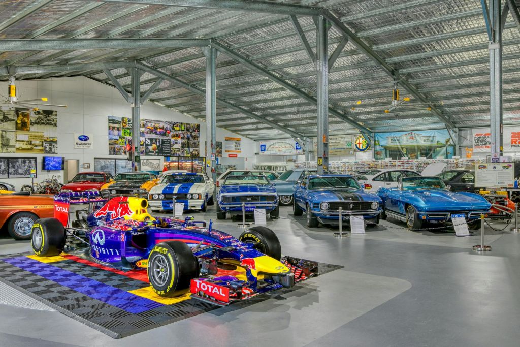 포뮬러 1 경주용 자동차와 빈티지 차량 등 다양한 클래식 및 현대 자동차가 전시된 쇼룸입니다.