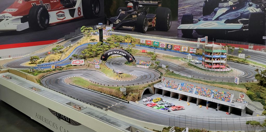 나무, 다리, 그랜드스탠드 등의 미니어처로 둘러싸인 곡선형 트랙에서 자동차를 타고 경주를 즐겨보세요.