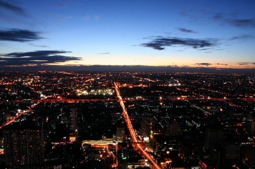 해질 무렵 가로등이 비추는 거리와 밤으로 바뀌는 맑고 푸른 하늘이 있는 도시의 공중 전망.