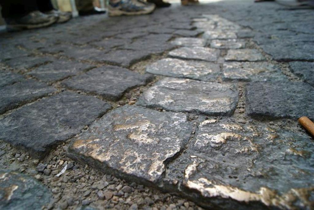 포장된 거리에서 신발과 다리가 흐릿하게 보이는 마모된 자갈의 클로즈업.