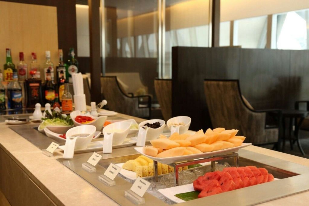 현대적인 식사 공간의 카운터에 슬라이스 과일, 샐러드, 조미료가 구비된 뷔페가 준비되어 있습니다.