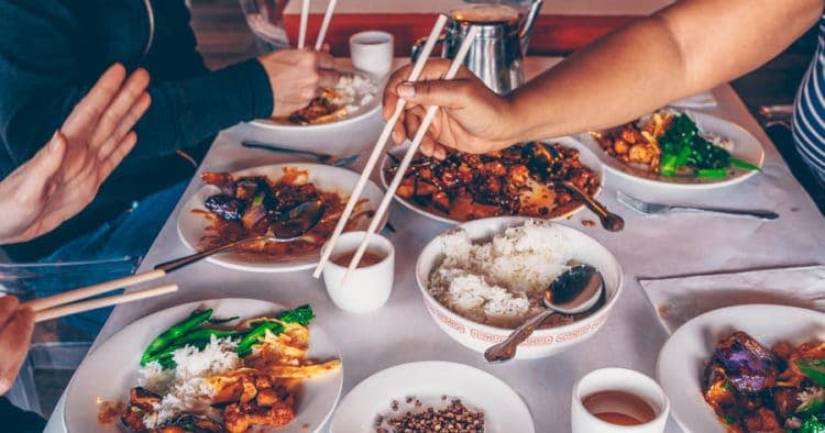 밥과 볶음 등 중국 음식 요리가 담긴 테이블로, 사람들이 젓가락을 사용하여 식사를 합니다.