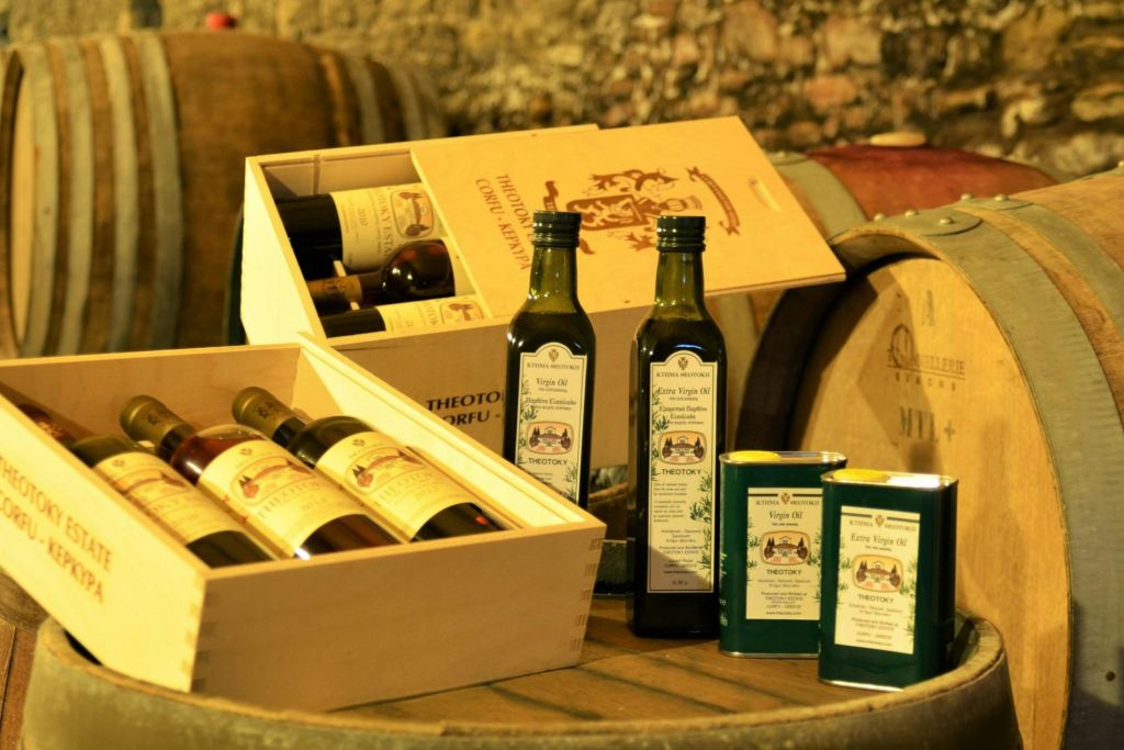 소박한 배경의 나무 통에 와인 병, 올리브 오일 병 2개, 올리브 오일 통 2개가 담긴 나무 상자.