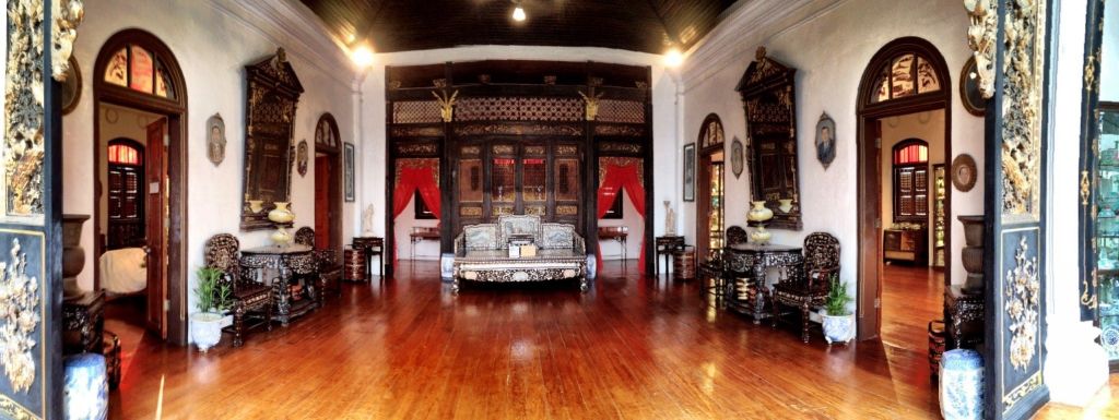 나무 바닥, 정교한 가구, 빨간색 커튼, 벽과 천장에 장식 요소가 있는 화려한 객실입니다.