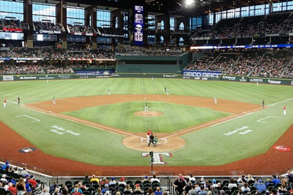 경기장에서 진행 중인 야구 경기로, 경기장에 있는 선수들과 관중들이 관중석에 서 있습니다.