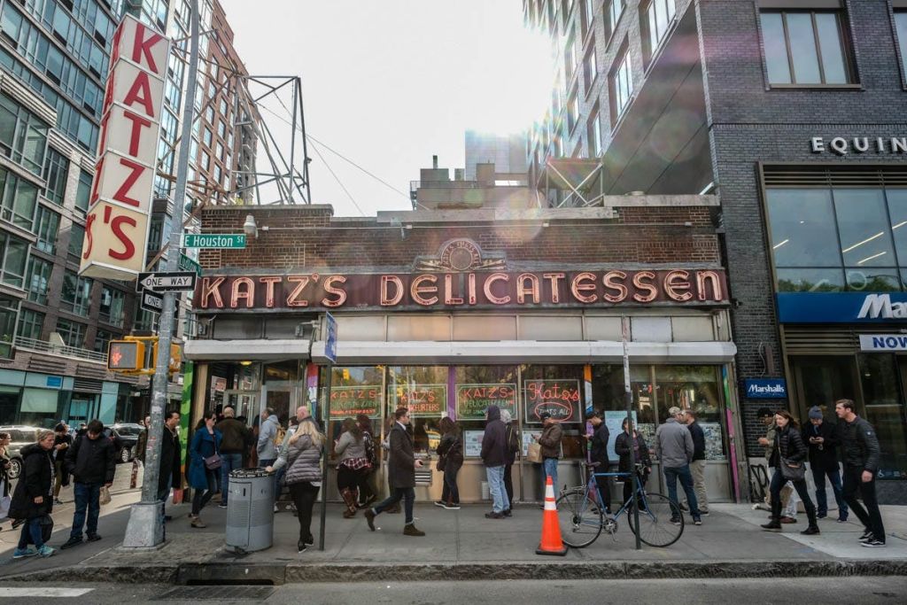 카츠의 델리카트슨 바깥에는 자전거와 입구 근처에 건설 콘이 있는 번화가에 사람들이 줄지어 서 있었습니다.