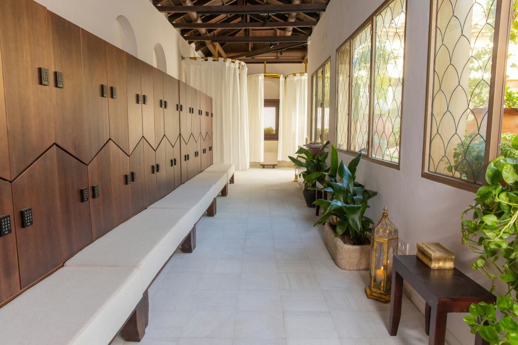 왼쪽에는 나무 사물함이 있는 복도, 벤치, 오른쪽에는 화분, 자연광이 들어오는 창문이 있습니다.