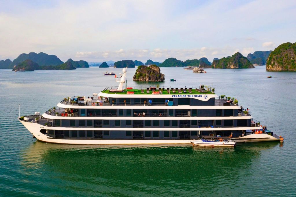 석회암 섬과 잔잔한 바다가 있는 경치 좋은 만에 "VELAR OF THE SEAS" 라는 이름의 멀티 데크 크루즈선이 있습니다.
