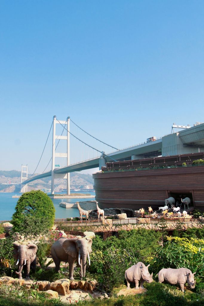 다양한 동물 조각품으로 둘러싸인 노아의 방주를 닮은 대형 목조 건물로, 물 위 현수교 근처에 있습니다.