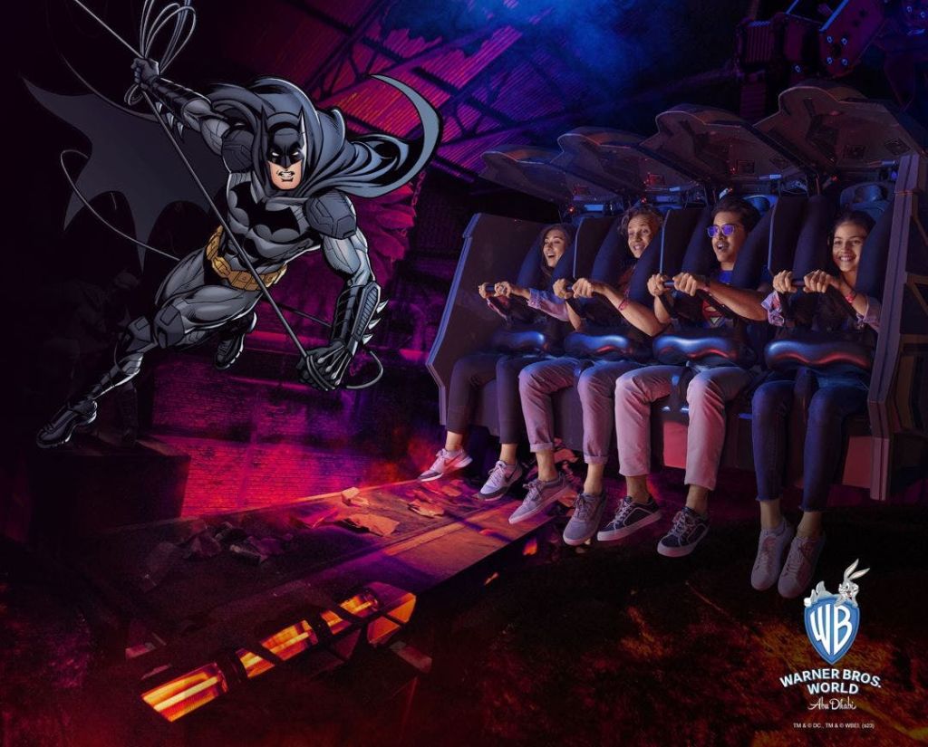 워너 브라더스 월드 (Warner Bros. World) 에서 배트맨을 테마로 한 놀이 기구에서 웃으며 앉아 있는 네 명의 사람들.