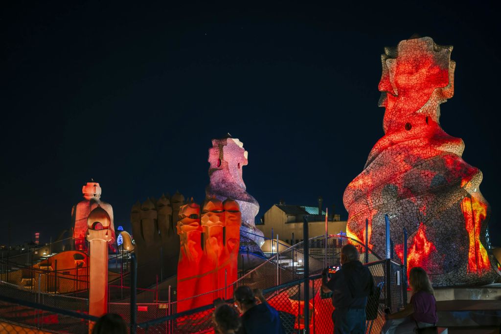 밤에는 옥상에 있는 관광객들이 유명한 건축 현장에서 화려하고 밝고 추상적인 석조 조각품을 감상합니다.