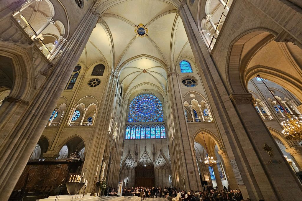 높은 아치형 천장, 스테인드글라스 창문, 아치형 출입구, 수많은 사람들이 모여 있는 커다란 대성당의 내부.