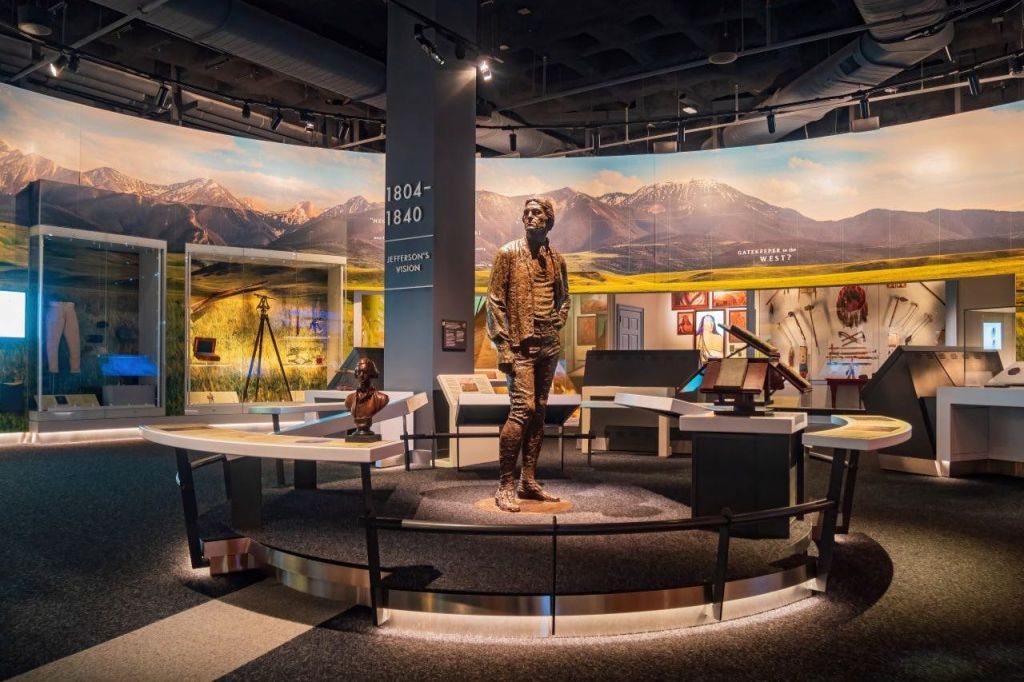 남자의 동상, 디스플레이 테이블, 정보 패널, 산 벽화를 배경으로 한 박물관 전시물.