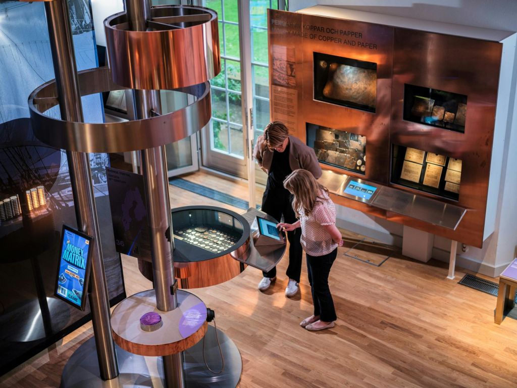 대화형 디스플레이와 금속 구조물이 있는 현대 미술관의 전시물을 살펴보는 두 사람.