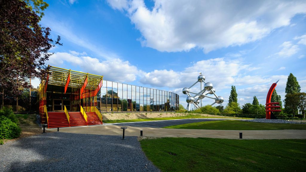 다채로운 색상의 산업용 계단에 인접한 현대적인 미러링 건물로, 멀리 금속 구형 조형물이 있습니다.