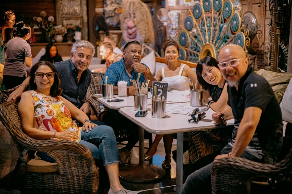 활기차고 다채로운 분위기의 레스토랑에서 5명의 일행이 테이블에 둘러앉아 있습니다.