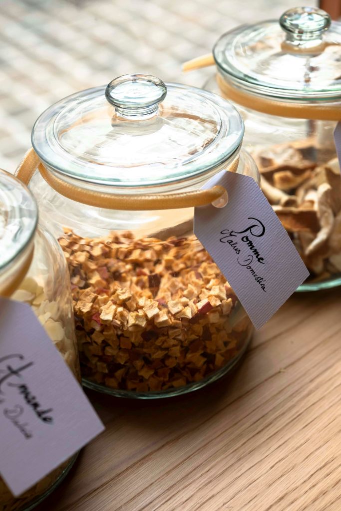 말린 과일로 채워진 유리 항아리에 문자열에 태그가 표시되어 있으며, 나무 표면에 자연 채광으로 표시됩니다.