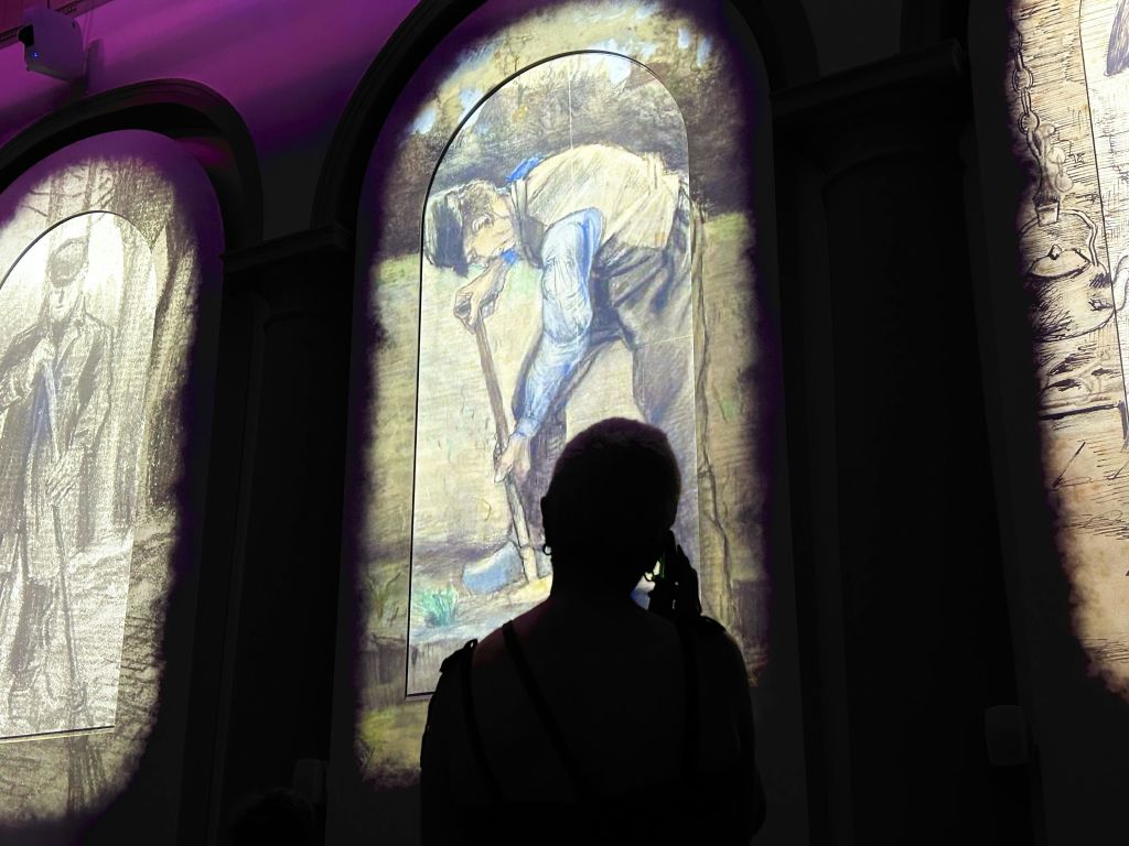 사람은 아치형 창문에 표시된 파고 있는 남자의 조명된 작품을 관찰합니다.