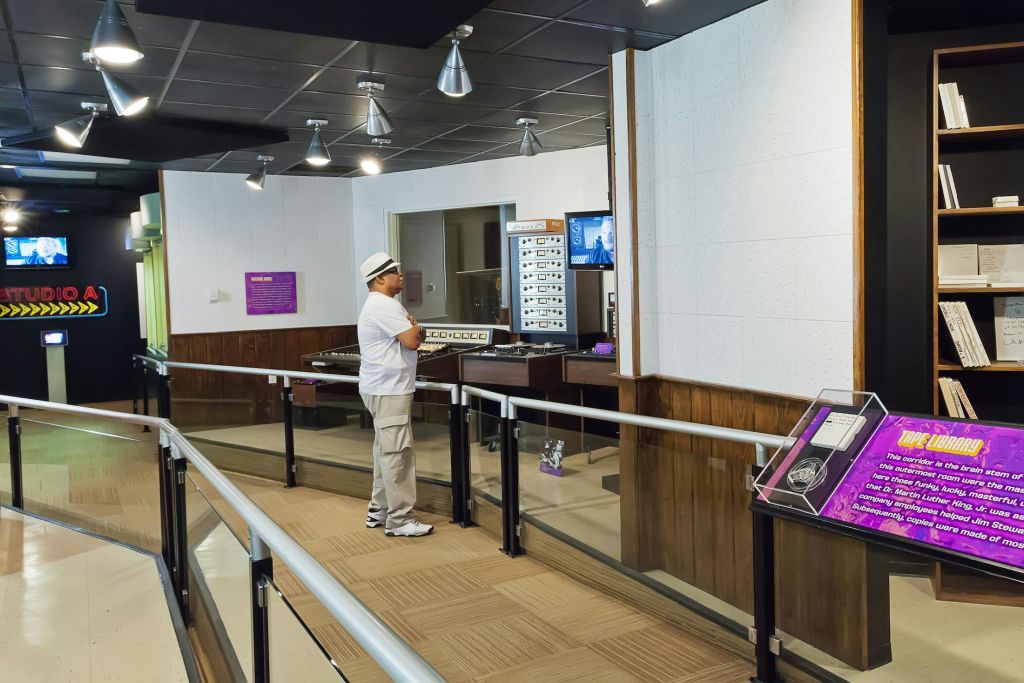 한 사람이 현대적인 전시실에 서서 정보 패널과 스크린이 있는 전자 장비 디스플레이를 보고 있습니다.