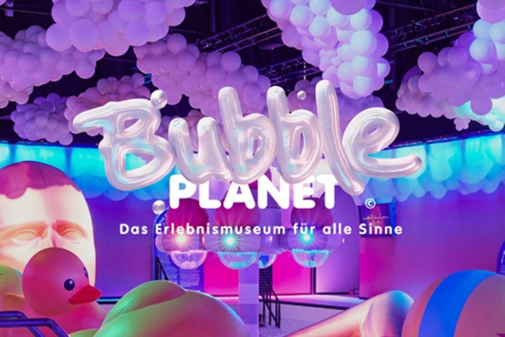 화려한 조명과 흰색 풍선을 갖춘 'Bubble Planet' 및 'Das Erlebnismuseum für alle Sinne' 텍스트가 있는 디스플레이.