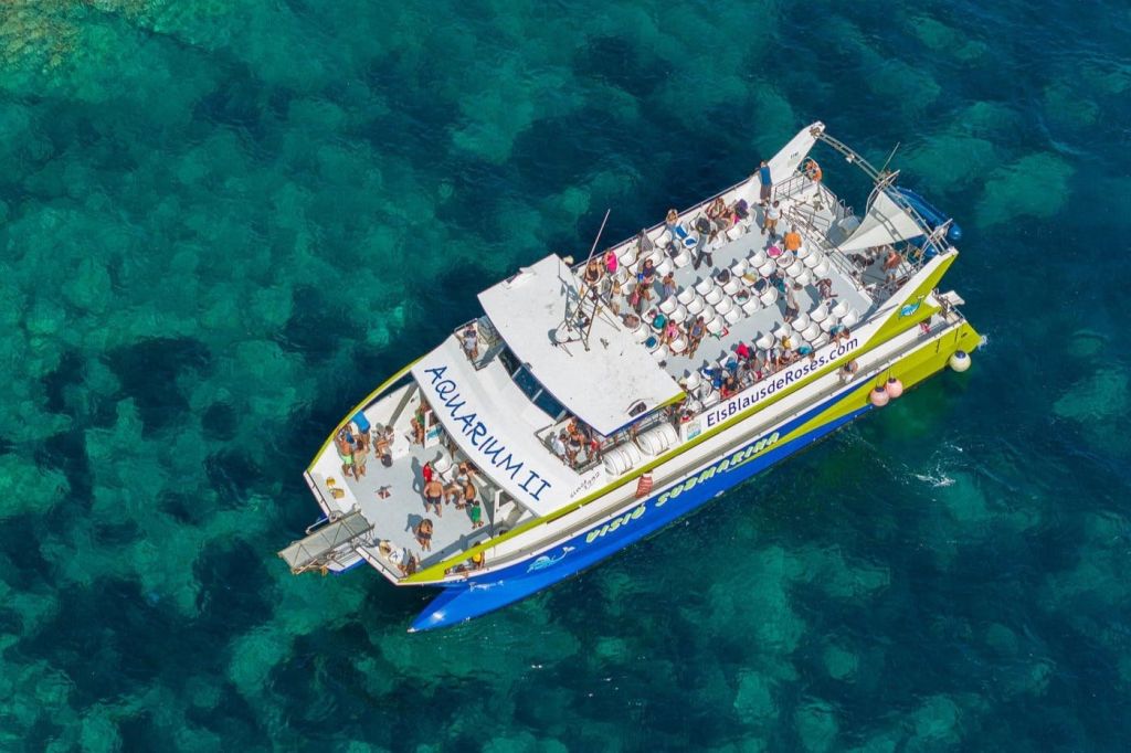 청록색의 맑은 물 위에 떠 있는 사람들이 있는 아쿠아리움 II (Aquarium II) 라는 이름의 보트의 공중 전망.
