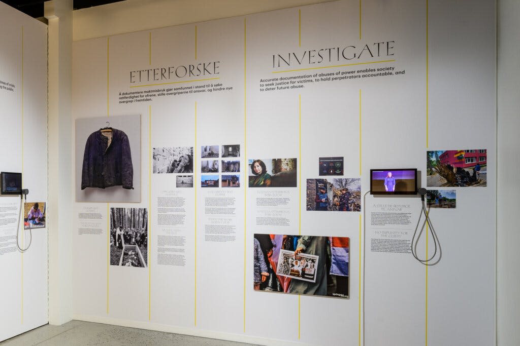사진, 텍스트 및 작은 비디오 화면을 표시하는 "ETTERFORSKE" 및 "INVESTIGATE" 라는 제목의 벽면 전시.