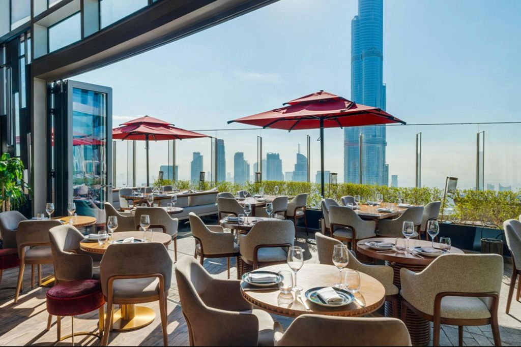 붉은 우산, 테이블, 높은 고층 빌딩을 배경으로 한 도시 스카이라인이 있는 야외 레스토랑 테라스.
