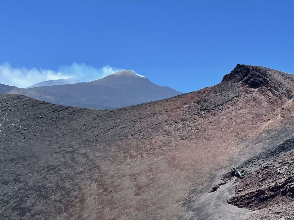 흡연 분화구, 험준한 지형, 맑고 푸른 하늘을 배경으로 한 화산 지형.