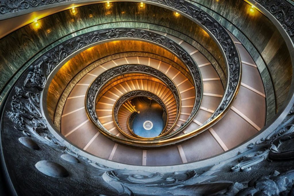 따뜻한 조명과 정교한 디테일이 특징인 화려한 난간이 있는 나선형 계단.