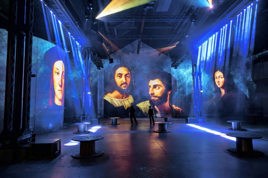 커다란 르네상스 초상화와 걷고 있는 두 명의 실루엣이 어둡게 빛나는 전시 공간입니다.