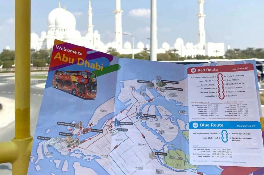 흰색 모스크를 배경으로 빨간색과 파란색 투어 루트가 있는 아부다비 지도가 있는 오픈 브로셔.