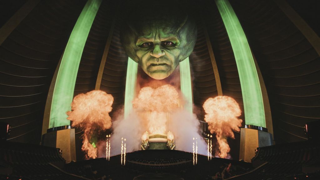 불타는 불꽃놀이 위에 빛나는 눈을 가진 커다란 녹색 머리와 어둡고 아치형 분위기의 연기.