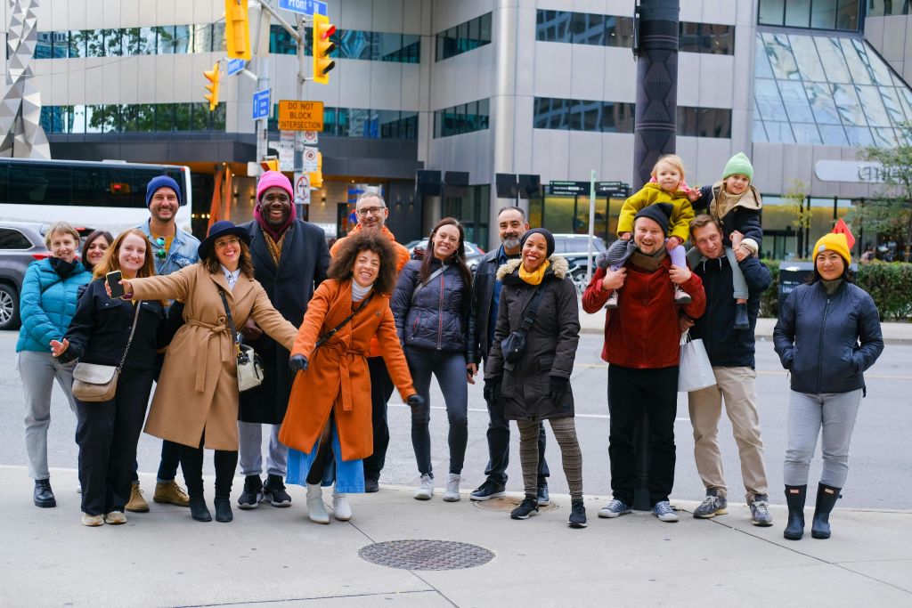 건물과 교통 표지판을 배경으로 도시의 인도에서 함께 웃으며 포즈를 취하는 사람들.