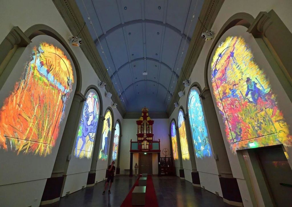 화려한 스테인드글라스 창문과 맨 끝에 웅장한 오르간이 있는 교회 같은 홀에 한 사람이 서 있습니다.