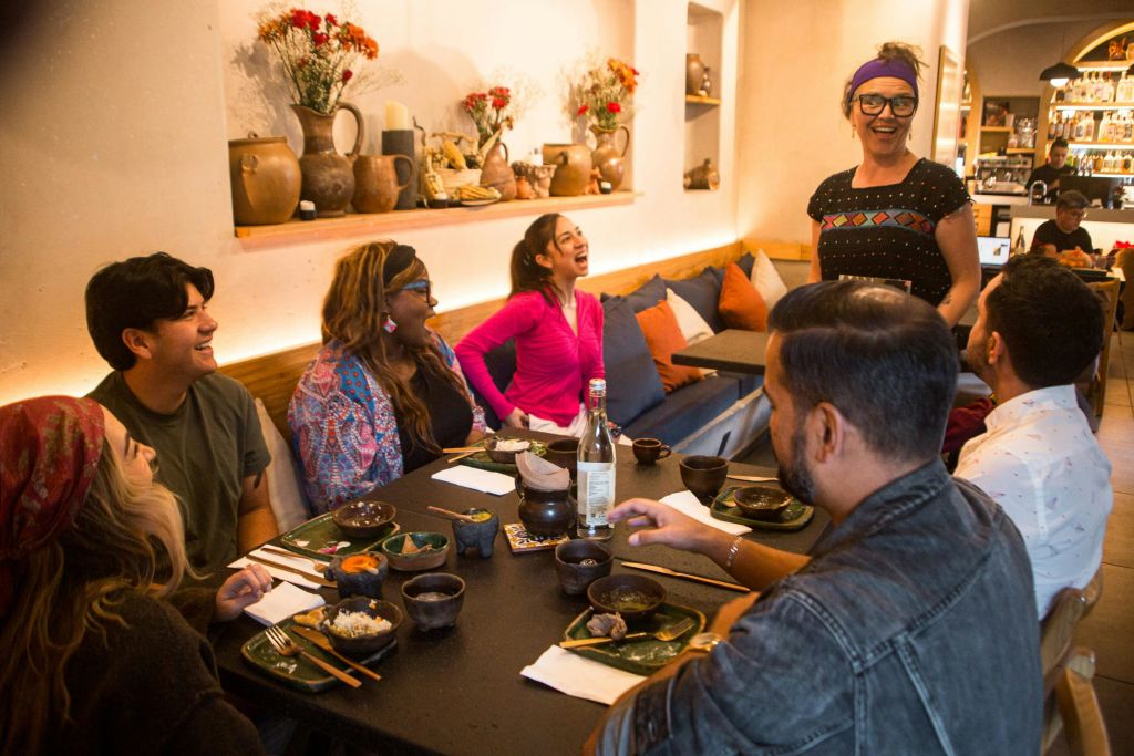 한 무리의 사람들이 아늑한 레스토랑의 테이블에 둘러앉아 함께 웃으며 식사를 즐기고 있습니다.