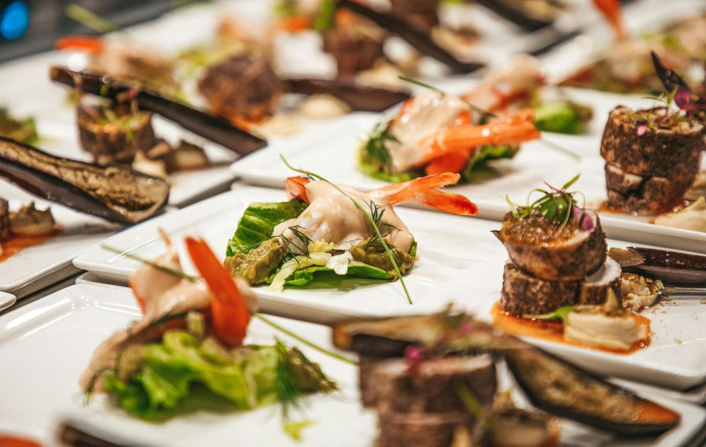 새우, 채소, 장식이 들어간 고급 애피타이저가 테이블 위에 깔끔하게 배열되어 있습니다.