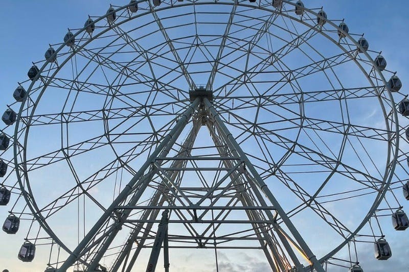 맑고 푸른 하늘 아래 금속 프레임워크가 있는 대형 대관람차 구조.