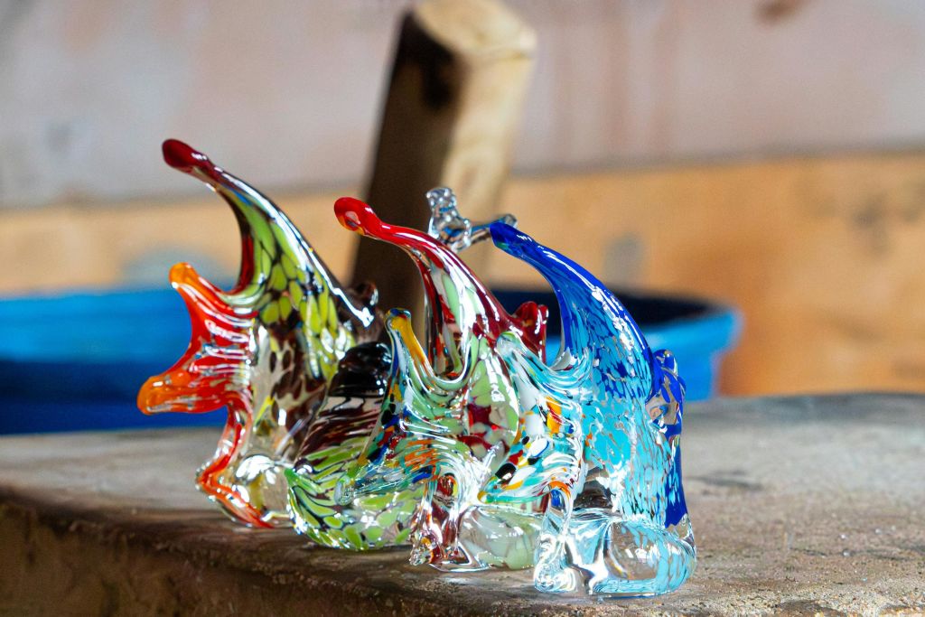 나무 표면에 물고기를 닮은 화려하고 정교하게 디자인된 유리 조각품. 흐릿한 배경.