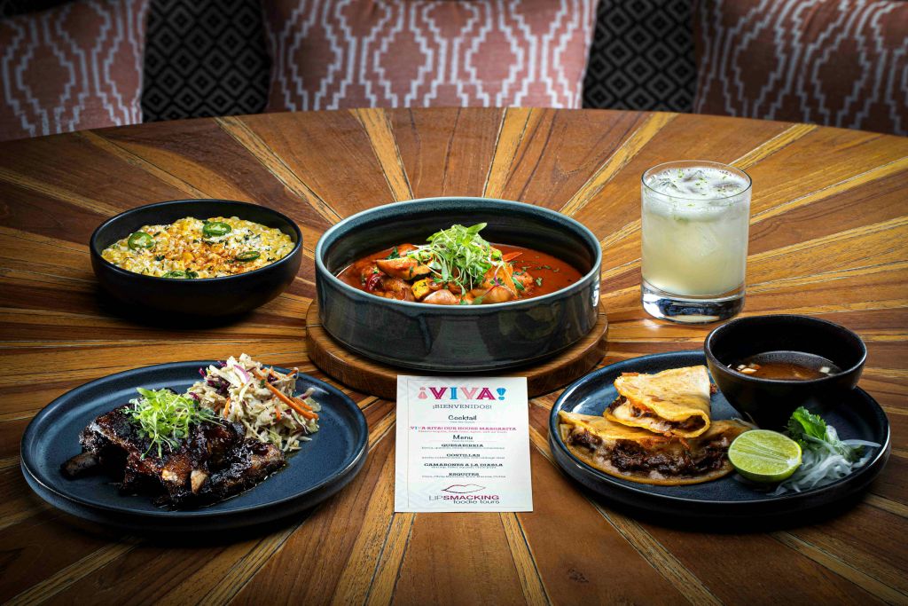 중앙에 메뉴카드와 함께 카레, 타코, 밥, 음료 등 다양한 메뉴가 세팅된 원목 테이블입니다.