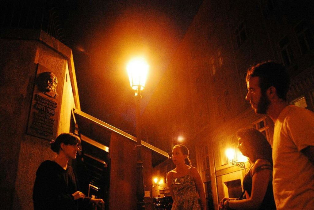 밤에 어두운 도시의 거리에서 밝은 가로등 아래에서 네 사람이 이야기를 나누고 있습니다.