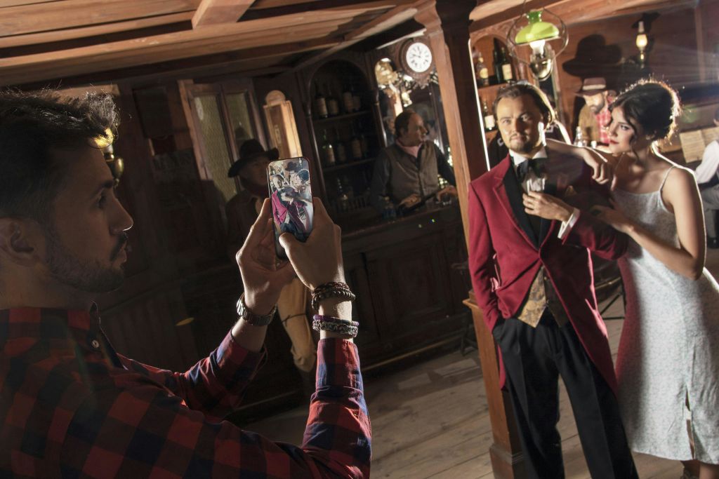 빨간 코트를 입은 사람과 흰색 드레스를 입은 여성이 빈티지 바에서 사진을 찍는 동안 포즈를 취하고 있습니다.