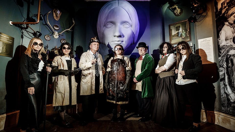 메리 셸리의 머리의 커다란 동상 앞에서 소름 끼치는 사이버 펑크 의상을 입은 사람들