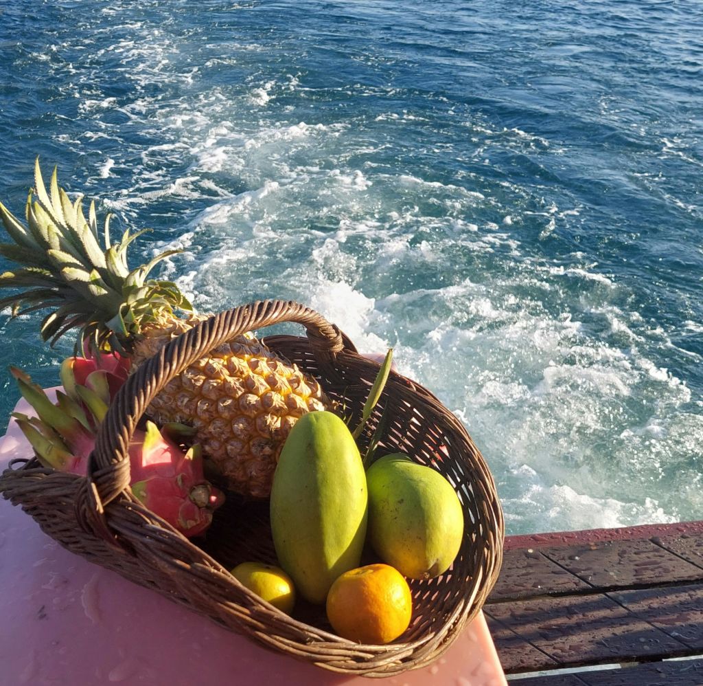 바다에서 깨어난 보트에 파인애플, 망고, 드래곤 과일 등 열대 과일로 가득한 바구니.