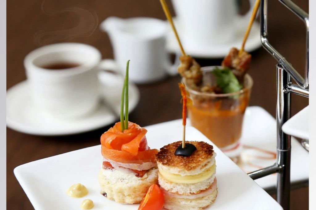 작은 샌드위치와 꼬치가 특징인 고급 애피타이저 플레이트에 차 세트를 배경으로 합니다.