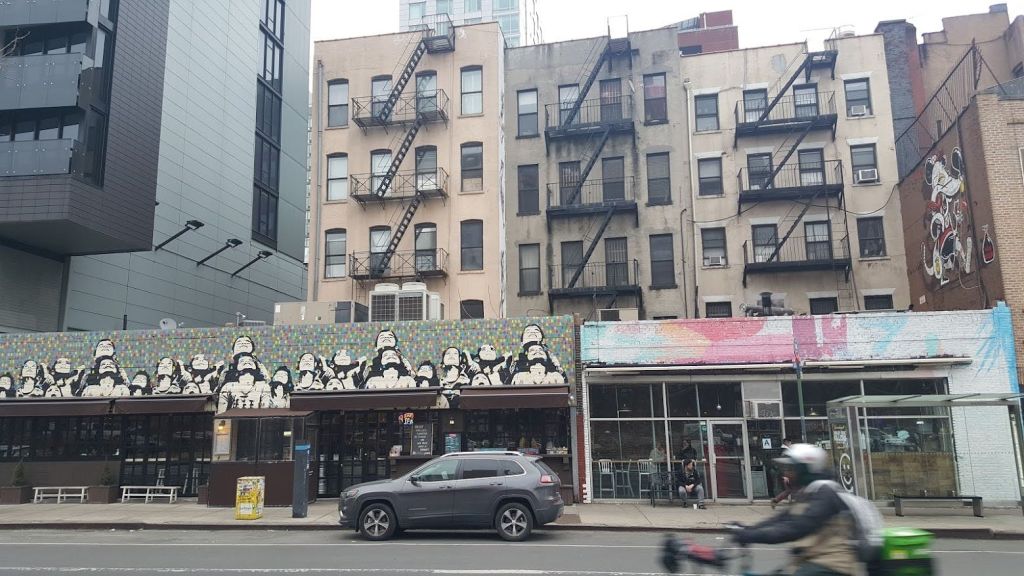 건물에 스톰 트루퍼 벽화가 있고, 인접 건물에 불이 나며, 자동차가 지나가는 도시 거리입니다.