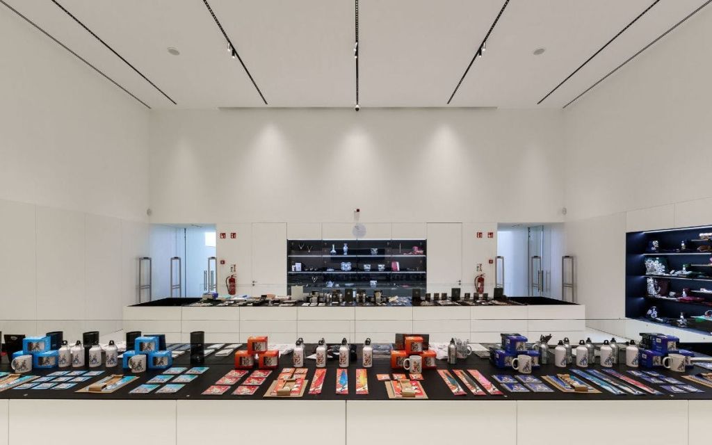 검은색 테이블에 깔끔하게 정리된 머그잔과 장신구 등 다양한 품목을 진열한 세련된 흰색 벽이 있는 현대적인 소매점.