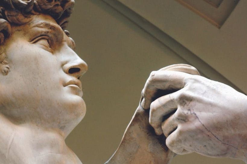 곱슬머리를 한 남성의 얼굴의 대리석 조각상을 클로즈업하여 가슴 가까이에 물건을 들고 있습니다.