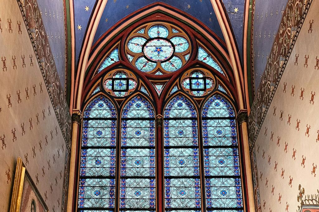 아치형 고딕 양식의 대성당 건축물에 정교한 파란색과 빨간색 패턴이 있는 스테인드글라스 창문에는 별이 빛나는 파란색 천장이 있습니다.